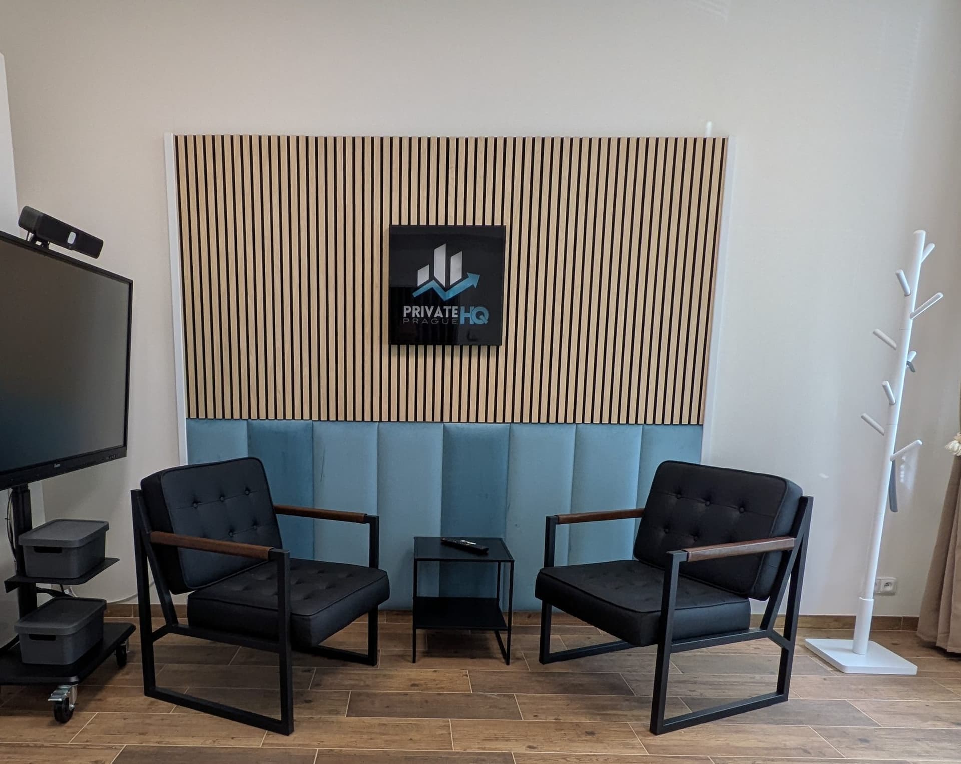 Lamellenwand im Besprechungsraum mit hinterleuchtetem Display und zwei Sesseln davor